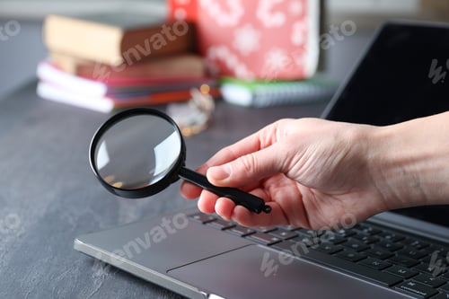 Preview: Magnifying glass in hand and laptop on wooden background