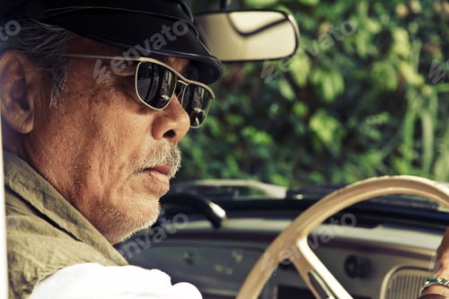 Preview: image of older man with glasses driving a car