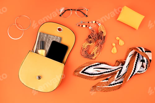 Preview: Flat lay with woman fashion accessories in yellow color over orange yellow textured background