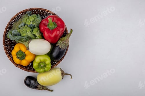 Preview: top view copy space colored bell peppers with broccoli in a basket with white and black eggplants on