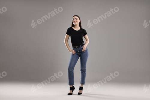 Preview: Smiling woman in stylish jeans on grey background