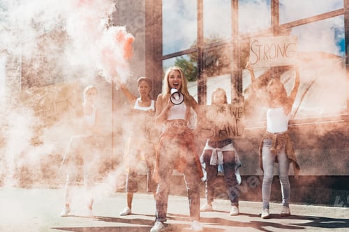 Visualização: visão de corpo inteiro de feministas multiétnicas gritando com alto-falante segurando cartazes com slogans