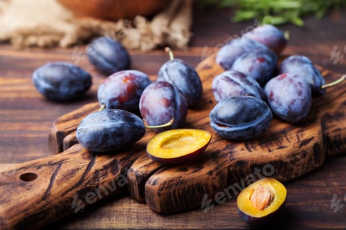 Preview: Fresh organic plums on rustic wooden cutting board