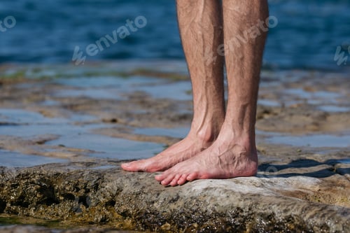 Preview: Male barefoot hairy legs with sea background.