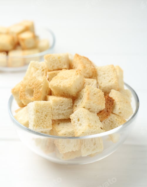 Preview: Delicious crispy croutons on white wooden table, closeup. Space for text