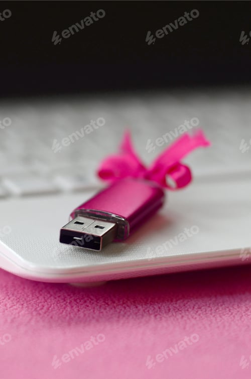 Preview: Brilliant pink usb flash memory card with a pink bow lies on a blanket