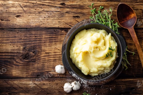 Preview: Mashed potatoes, boiled puree in cast iron pot on dark wooden rustic background, top view