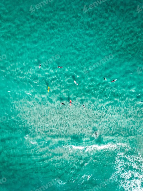 Preview: Vertical overhead shot surfers with surfboards on a clear blue sea