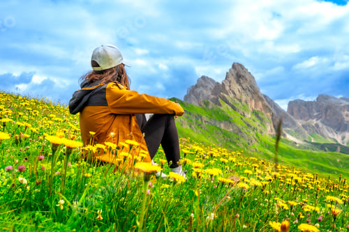 Preview: Tourist relaxing in a meadow enjoying the seceda peaks in the dolomites
