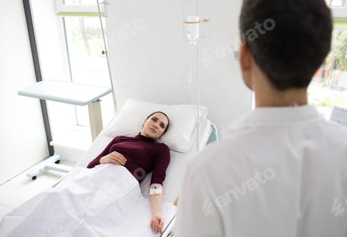Preview: A healthcare professional attends to a patient lying in a hospital bed, equipped with IV drip