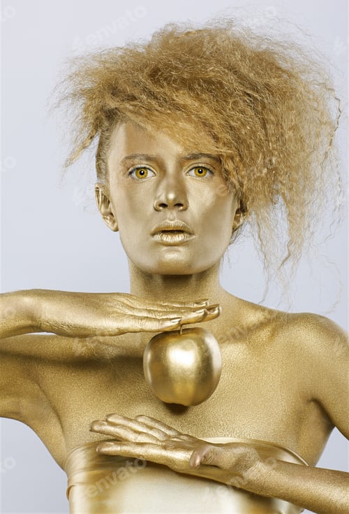 Preview: Portrait Of Girl With Golden Bodyart Posing With Golden Apple In Her Hands On Gray