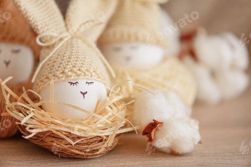 Preview: Easter eggs in crochet knitted hats with rabbit ears in nest. Easter celebration concept