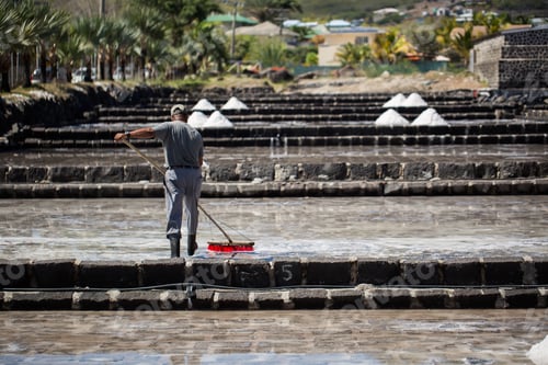 Preview: People collect the salt on a Sunny day on the shores of the Indian ocean in Mauritius.