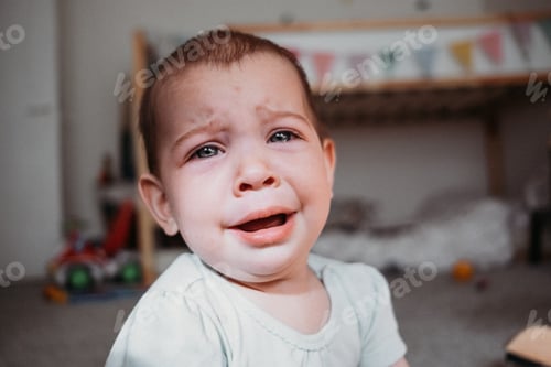 Preview: Infant baby crying in nursery at home. Eyes full of tears