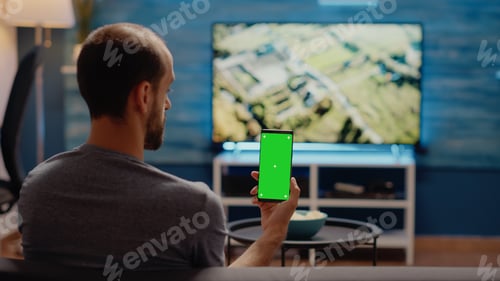 Preview: Caucasian man vertically holding smartphone with green screen