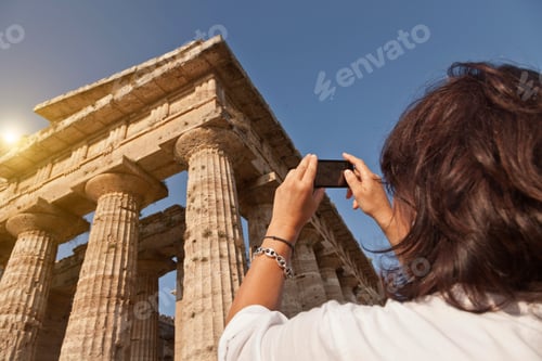 Preview: Tourist capturing the grandeur of ancient ruins on her smartphone.
