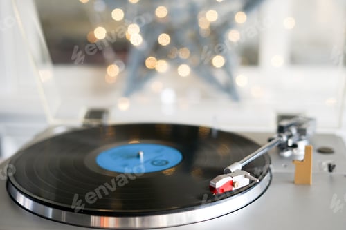 Preview: Close-up of vinyl record player, playing Christmas carols. Bokeh lights in the background.