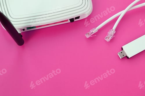 Preview: Internet router, portable USB wi-fi adapter and internet cable plugs lie on a bright pink backgroun