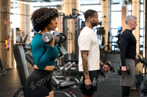 Vista previa: Diverse people exercising with dumbbells performing bicep curls at gym
