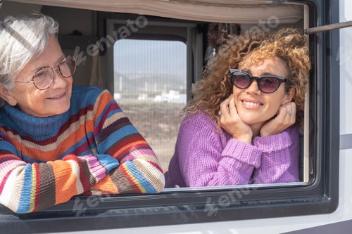 Preview: Portrait of attractive happy caucasian women traveling in camper motor home looking out the window