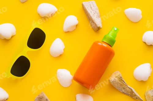 Preview: Top view of sunblock near seashells and sunglasses on yellow background