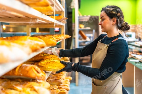 Preview: Woman arranging artisan bread from shelf in the bakery shop