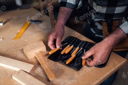 Preview: Close up of male carpenters hands choosing the carving tool.