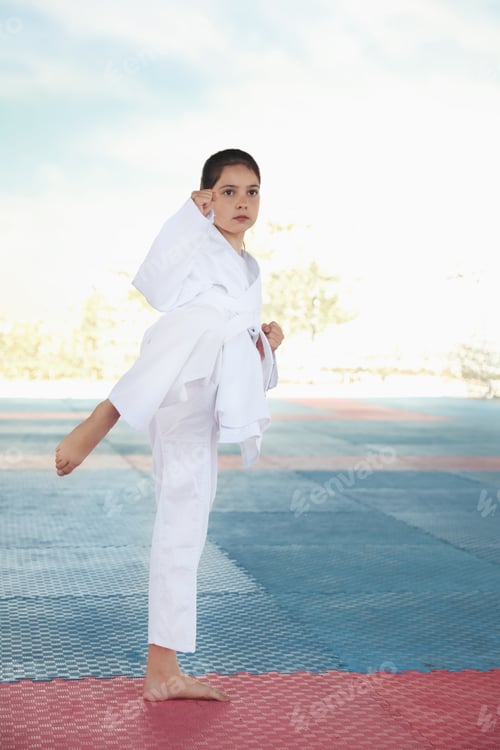 Preview: Girl in kimono practicing karate on tatami outdoors