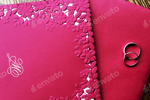 Preview: wedding invitation and rings are on a red envelope