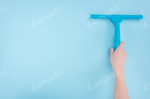 Preview: cropped view of woman holding squeegee on blue background