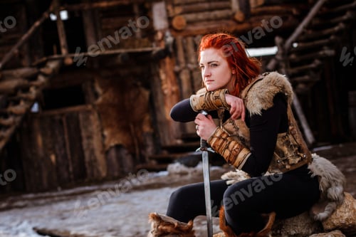 Preview: Red-haired woman is a Viking. Against backdrop of a village or an ancient settlement.