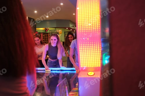 Preview: Young women playing air hockey in an amusement arcade