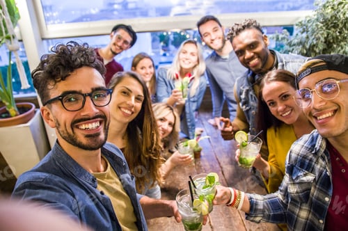 Preview: Happy friends taking a selfie at the restaurant drinking cocktails