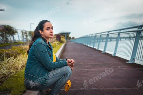 Preview: young latin woman sitting on the edge of the street