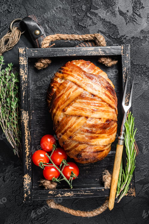 Preview: Roast bacon wrapped meatloaf, meat loaf in a tray with herbs. Black background. Top view