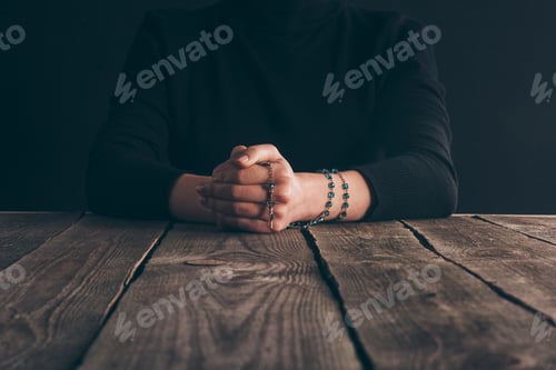 Preview: cropped image of nun sitting at table with rosary and praying