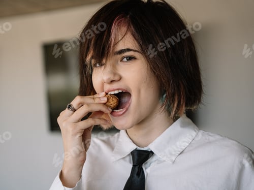 Preview: woman looking at the camera while trying to crack a walnut shell with her teeth