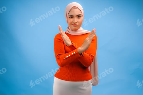 Preview: Pretty Asian Muslim woman wearing a hijab with hand gesture posing rejection or prohibition.