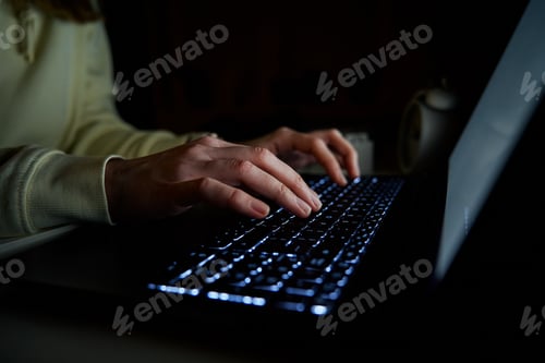 Preview: Anonymous woman working on laptop at night