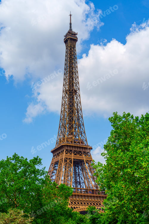 Preview: Iconic Eiffel Tower Amidst Verdant Trees Under a Blue Sky with Fluffy White Clouds, Paris