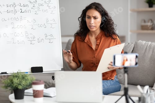 Preview: Female teacher explaining math online showing clipboard to laptop