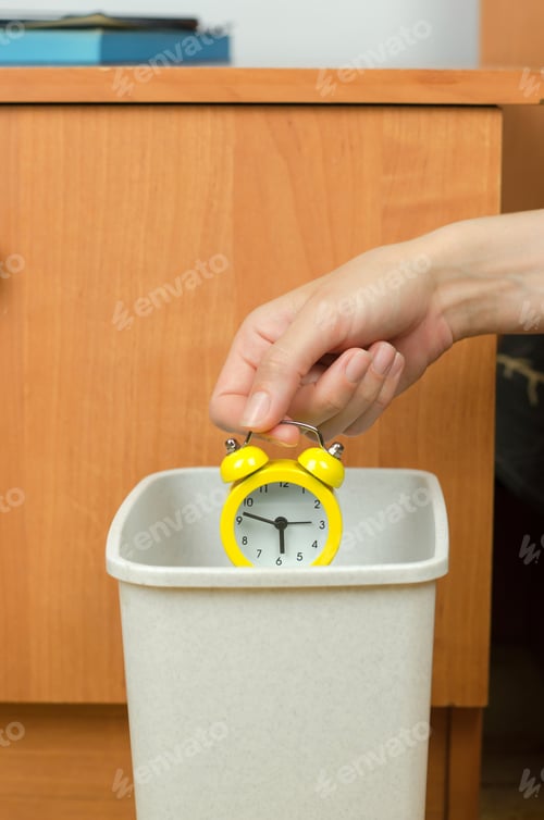 Preview: Woman's hand throws the alarm clock into the trash