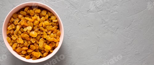 Preview: Golden Raisins in a Pink Bowl on a gray background, top view. Flat lay, overhead, from above.