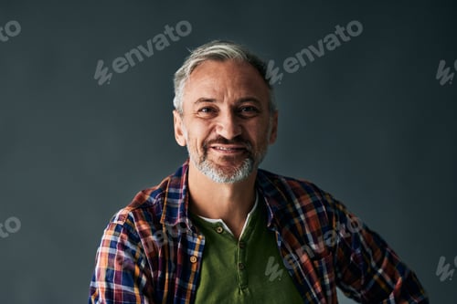 Vorschau: Porträt eines reifen Mannes, der in die Kamera schaut und wie ein Model posiert, auf grauem Hintergrund.