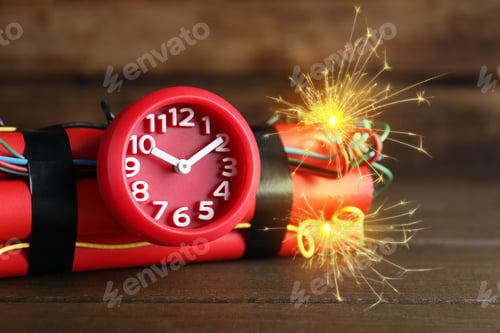 Preview: Dynamite time bomb with burning wires on wooden table, closeup