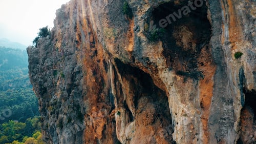 Preview: Eroded rocky cliff above green mountain valley.