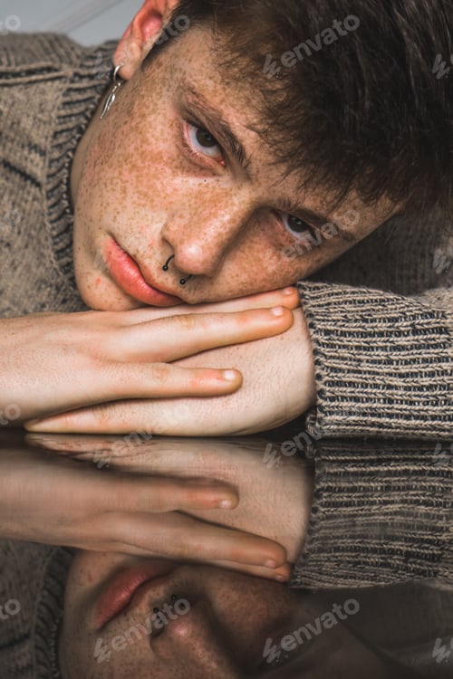 Preview: Freckled man in sweater lying on hands