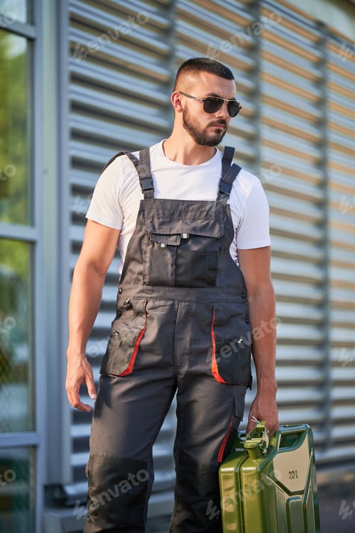Preview: Strong gas station worker holding canister full of fuel.