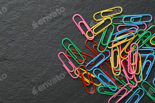 Preview: Many colorful paper clips on black table, top view. Space for text