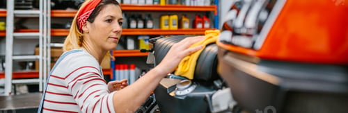 Preview: Mechanic woman cleaning motorcycle seat with cloth on factory